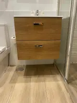 Wooden bathroom vanity with two drawers beneath the basin, beside the toilet, in the Interior Apartment